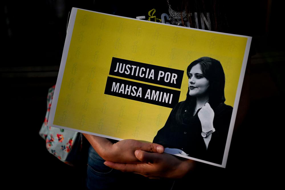 An activist holds a sign reading: “Justice for Mahsa Amini” during a protest over her death in Iran, outside the Iranian embassy in Buenos Aires, Argentina, on Septembre 27, 2022. - AFPPIX