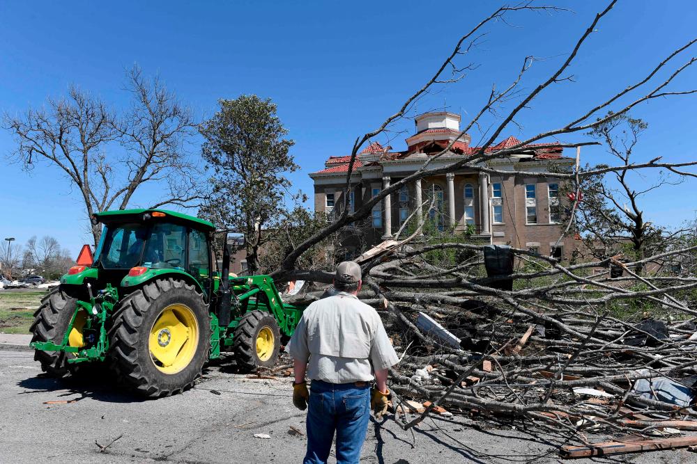 ROLLING FORK, MS - MARCH 25: Workers clear debris from damage from a series of powerful storms and at least one tornado in front of the Sharkey County courthouse on March 25, 2023 in Rolling Fork, Mississippi. AFPPIX