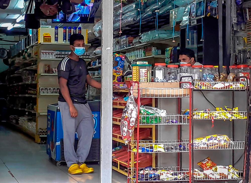 Two Bangladeshi workers tending to a shop after a semi-enhanced movement control order was lifted in Jalan Pudu, on May 30, 2020. — Sunpix by Adib Rawi