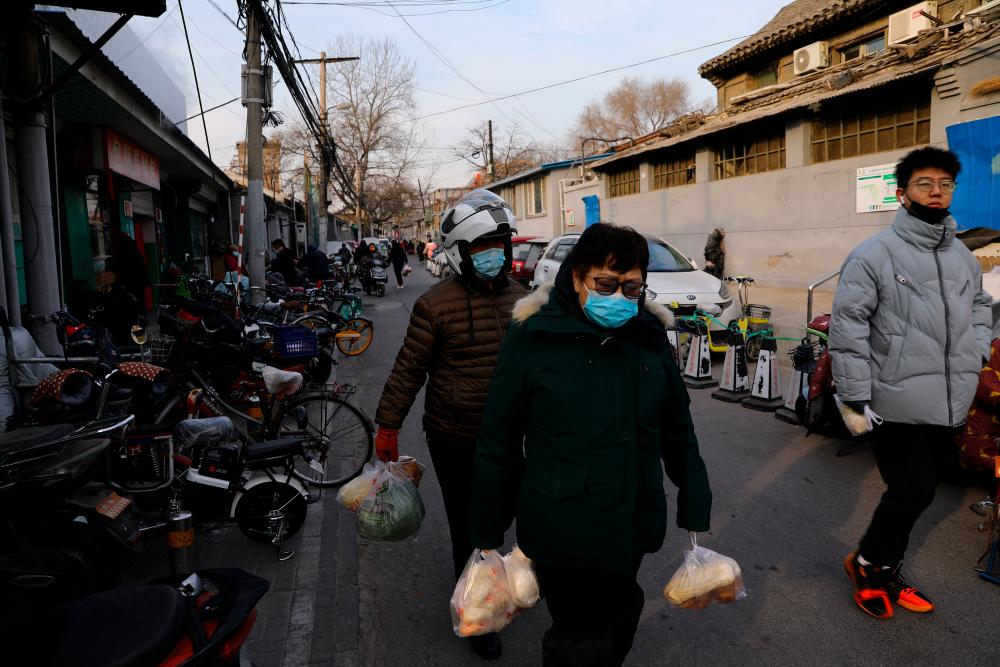People holding bags of food walk on a street, as the coronavirus disease (Covid-19) pandemic continues in the country, in Beijing, China January 14, 2022. REUTERSpix