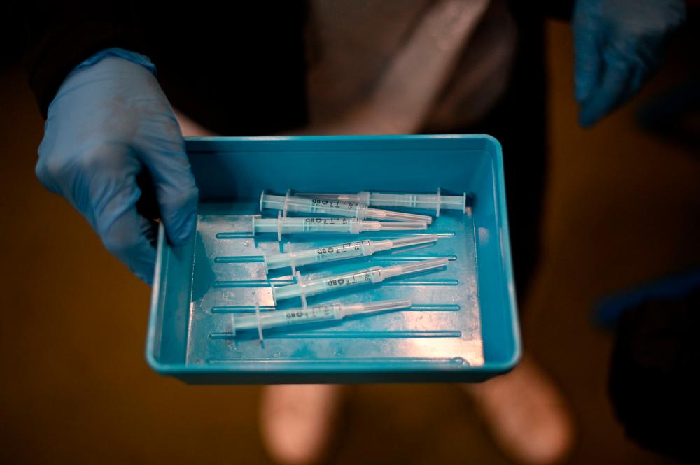 A clinician displays a tray of syringes filled with prepared doses of a Moderna Covid-19 booster vaccine at a temporary vaccination centre set up inside St John's Church in west London on December 4, 2021. Britain, which has been among the hardest hit by Covid-19 with more than 145,000 deaths, is racing to offer third doses of coronavirus vaccines to all adults aged over 18 through its state-run National Health Service. AFPpix