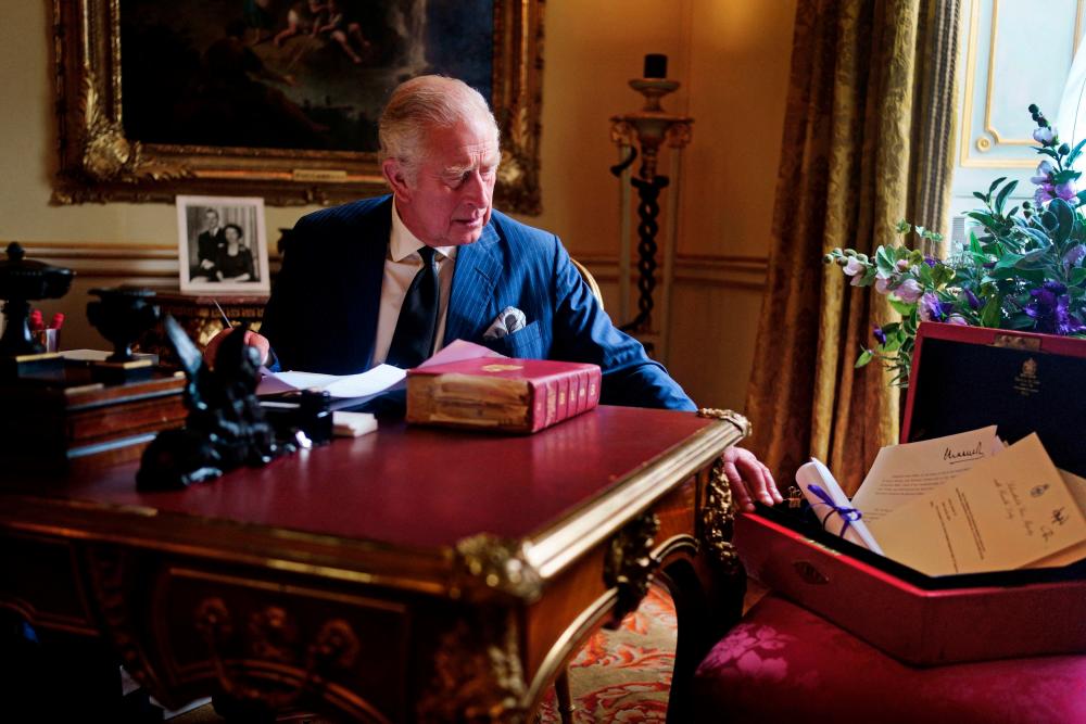 A Buckingham Palace handout image released on September 23, 2022, shows King Charles III carrying out official government duties from his red box in the Eighteenth Century Room at Buckingham Palace, London/AFPPix