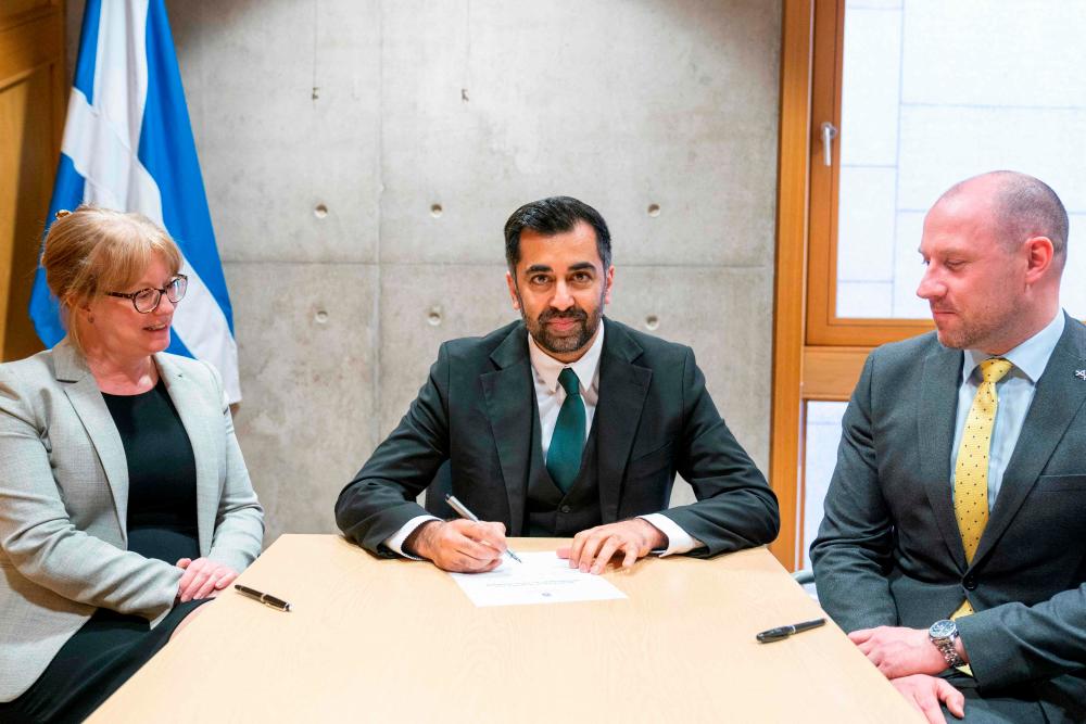 Newly elected leader of the Scottish National Party (SNP), Humza Yousaf (C), signs the nomination form to become First Minister for Scotland, flanked by his proposer Shona Robison (L) and seconder Neil Gray (R), at the Scottish Parliament in Edinburgh, ahead of the MP’s vote concerning his nomination to be Scotland’s sixth First Minister. AFPPIX