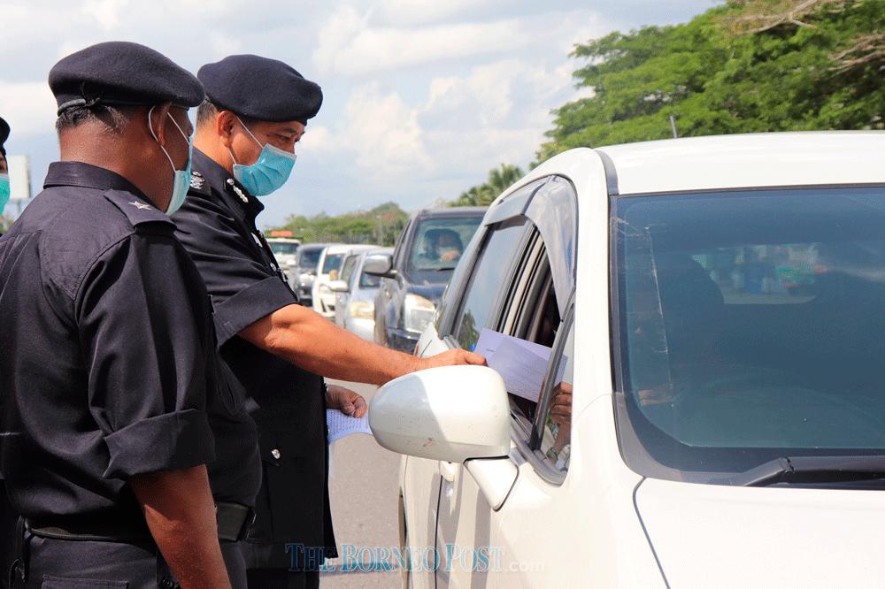 Sibu police chief ACP Stanley Jonathan Ringgit (second left) hands a leaflet on Covid-19 prevention to a motorist during a roadblock in Sibu in this file photo. — The Borneo Post