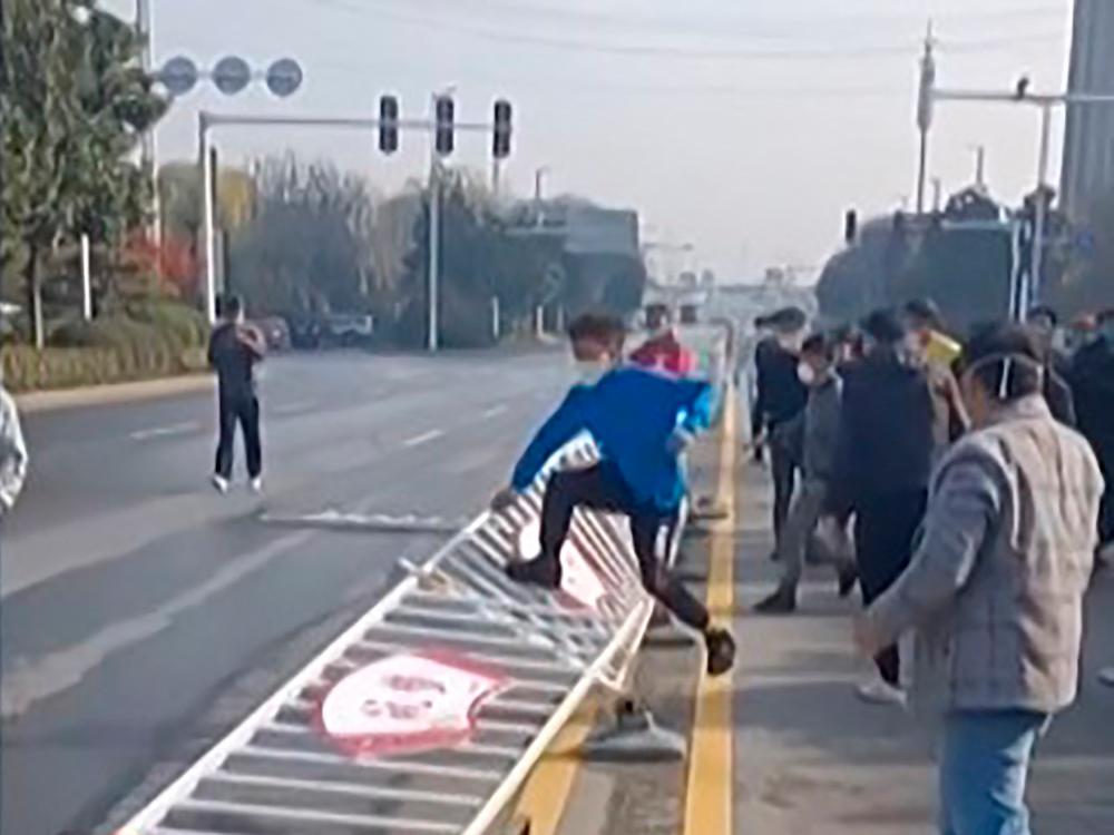 This image grab taken from AFP video footage and posted on November 23, 2022 shows workers at Foxconn’s iPhone factory in Zhengzhou in central China clashing with riot police. AFPPIX