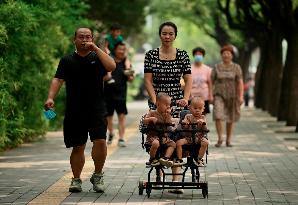 A woman pushes a trolley with twins along a street in Beijing on August 2, 2022. China's population will begin to shrink by 2025, officials said, as family sizes grow smaller and citizens age.AFPPIX