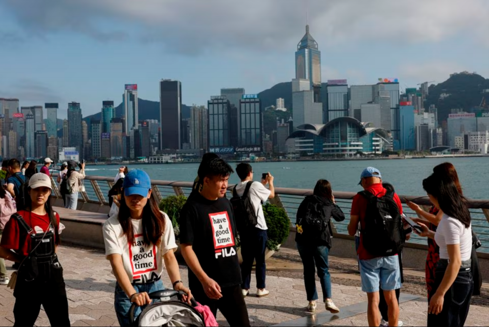 Mainland Chinese tourists walk in front of the skyline of buildings at Tsim Sha Tsui, in Hong Kong, China May 2, 2023. REUTERSpix