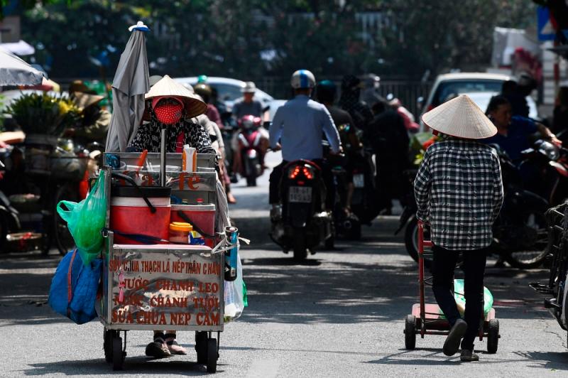 Street vendor Vu Thi Phuong (left) pushes her trolley to sell coffee and soft drinks in Hanoi//AFPix