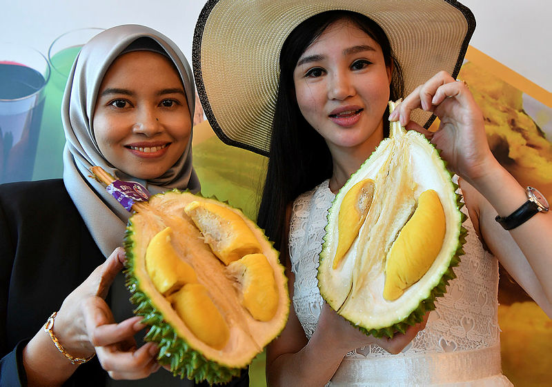 Nur Alifah Najwa Ramli from Beho Fresh with He Yuhan from Yechen, a China company, showing choice durian at the launch yesterday. — Bernama