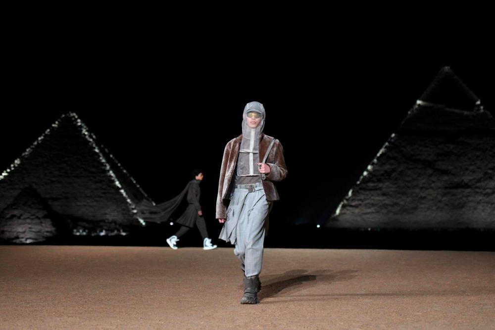 A model presents a creation at the Christian Dior fashion show at the Giza Pyramids Necropolis on the outskirts of the twin city of Egypt's capital on December 3, 2022. French fashion house Dior today held its first show at Egypt's ancient Giza pyramids, presenting its 2023 fall men's collection in the shadow of the of the millennia-old tombs. - AFPPIX
