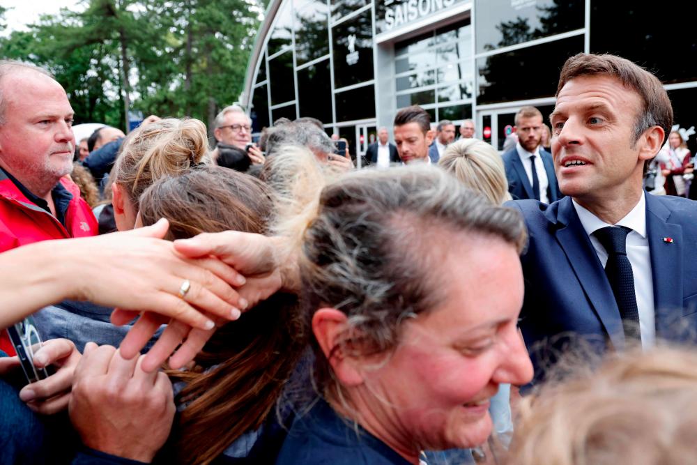 France's President Emmanuel Macron (R) shakes hands with onlookers he arrives to vote in the second stage of French parliamentary elections at a polling station in Le Touquet, northern France on June 19, 2022. AFPpix