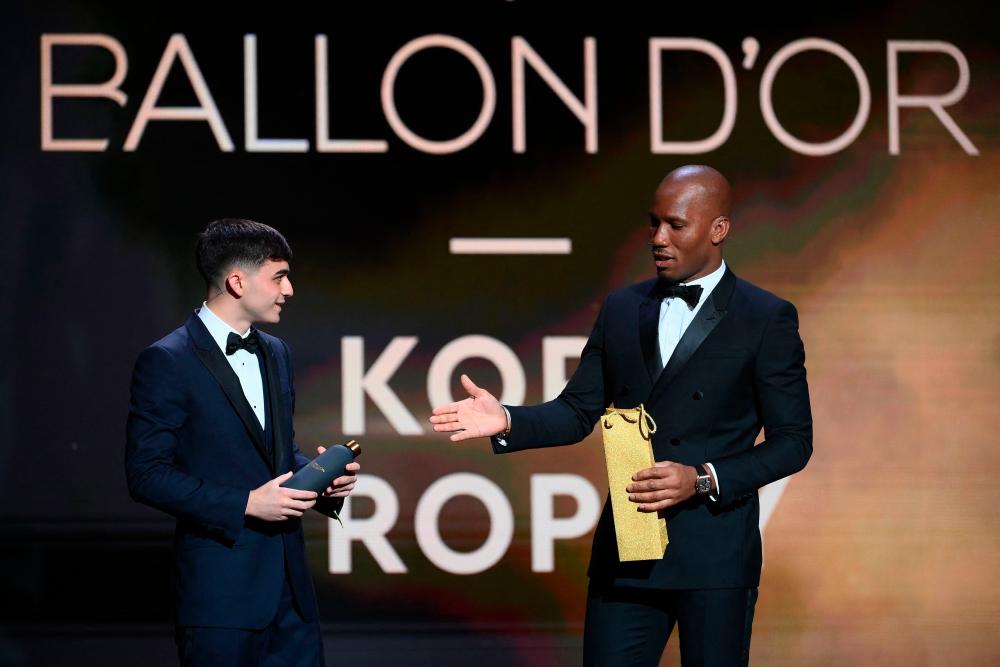 FC Barcelona's Spanish midfielder Pedri (L) receives a thermos as a present from Ivorian and host Didier Drogba during the 2021 Ballon d'Or award ceremony at the Theatre du Chatelet in Paris on November 29, 2021. -AFPpix