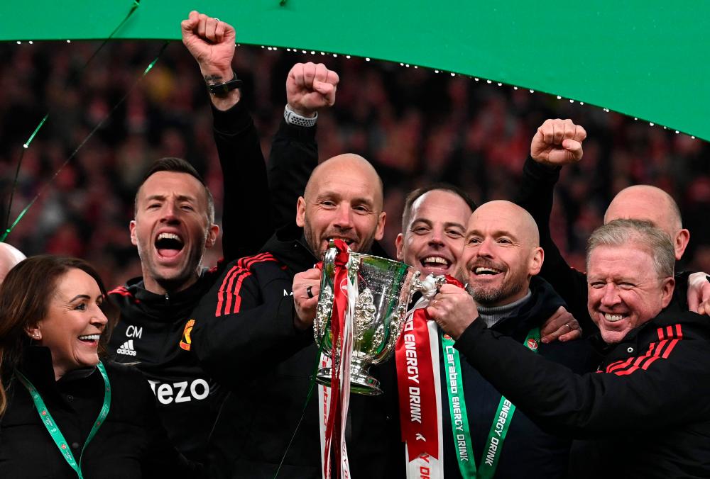 Manchester United's Dutch manager Erik ten Hag (3R) and his assistants celebrate with the trophy after their victory in the English League Cup final football match between Manchester United and Newcastle United at Wembley Stadium, north-west London on February 26, 2023. AFPPIX