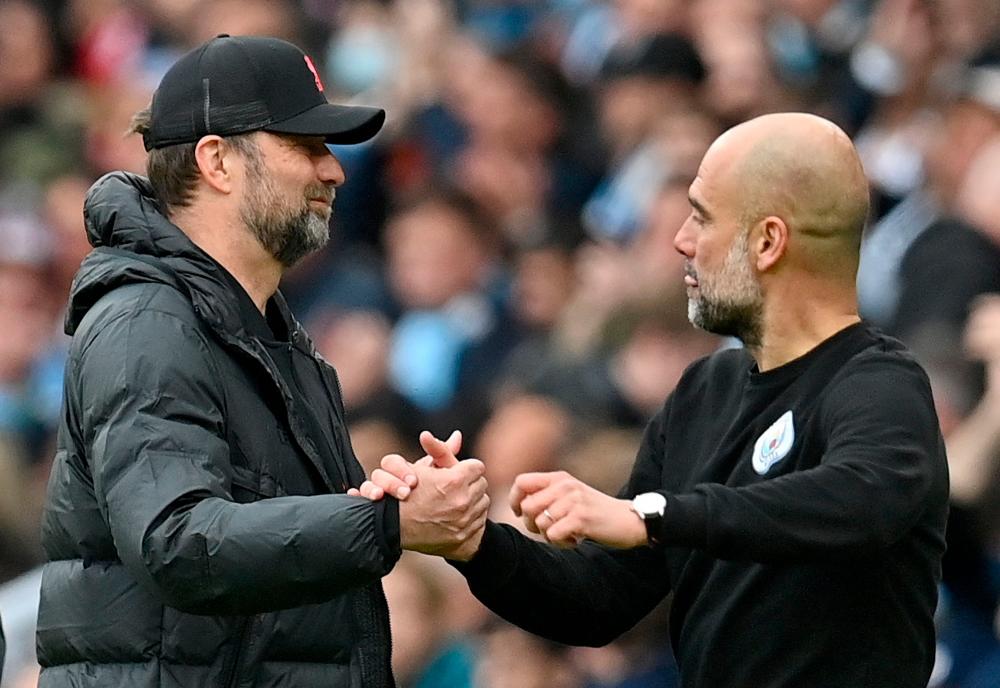 Liverpool's German manager Jurgen Klopp (L) shakes hands with Manchester City's Spanish manager Pep Guardiola after the English Premier League football match between Manchester City and Liverpool at the Etihad Stadium in Manchester, north west England, on April 10, 2022. The match ended 2-2. AFPPIX