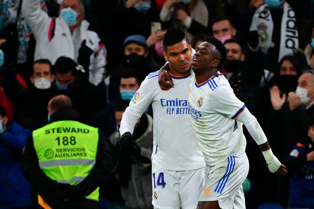 Real Madrid's Brazilian forward Vinicius Junior (right) celebrates with teammate Real Madrid's Casemiro after scoring a goal during the Spanish league football match between Real Madrid CF and Sevilla FC at the Santiago Bernabeu stadium in Madrid on November 28, 2021. -AFPPIX