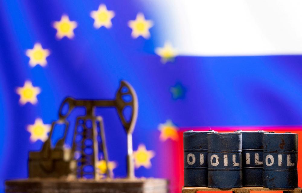 Models of oil barrels and a pump jack are seen in front of displayed EU and Russia flag colours in this illustration. – Reuterspic