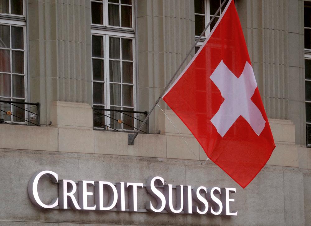 Switzerland’s national flag flies above a logo of Credit Suisse in front of a branch office in Bern, Switzerland. – Reuterspic