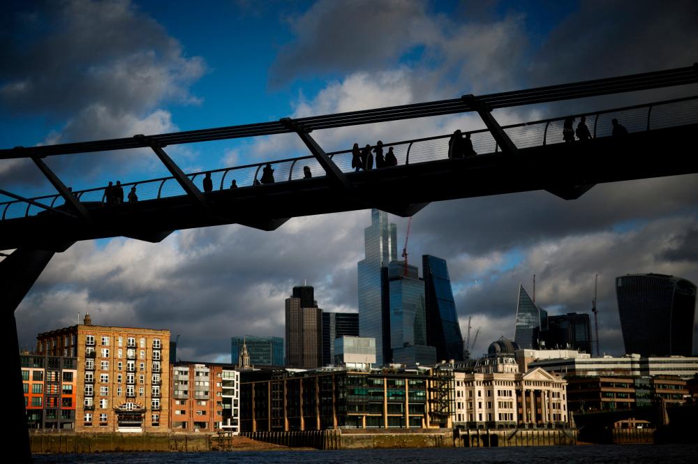 People walking on the Millennium Bridge with the City of London financial district in the background. Economists say Britain’s economy is losing momentum while its peers in the European Union seem to be gathering pace. – Reuterspic