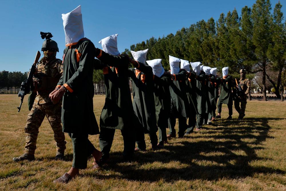 (FILES) In this file photo taken on February 2, 2021, Afghan security forces escort suspected Taliban fighters as they are being presented in front of the media after an operation at the National Directorate of Security (NDS) headquarters in Herat. Few nations endured as tumultuous a year as Afghanistan in 2021, and the country's woes are far from over as a bitter winter draws in. AFPpix