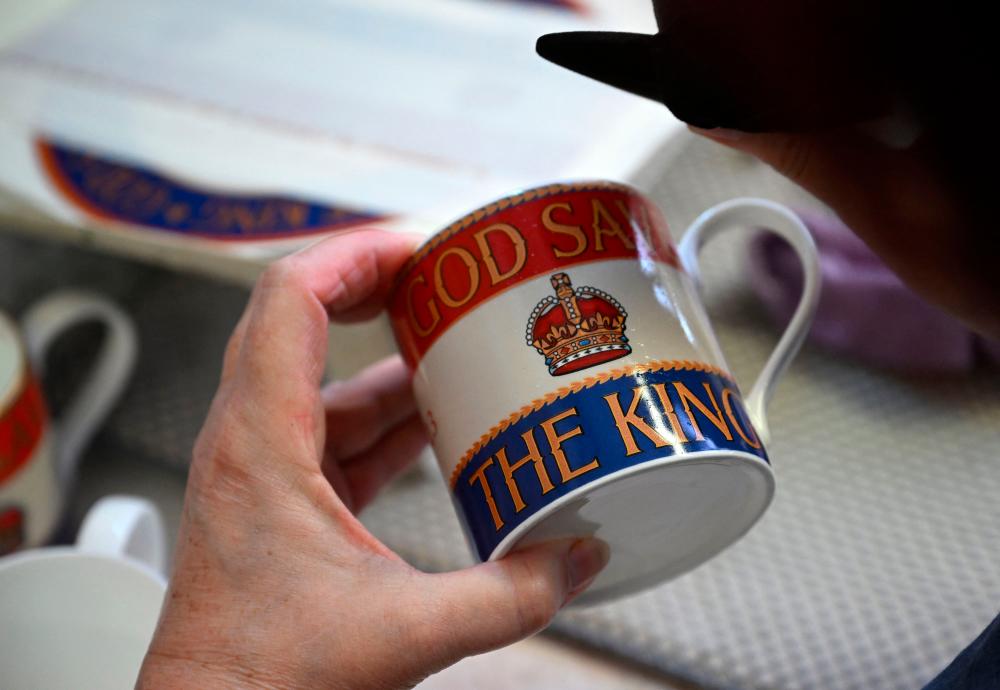 In this file photo taken on March 20, 2023 a pottery worker works on a range of fine bone china, designed to commemorate the coronation of Britain’s King Charles III, at Duchess China 1888 in Longton, central England. AFPPIX