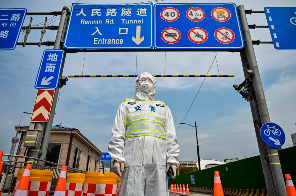 (FILES) In this file photo taken on March 28, 2022, a transit officer wearing protective gear controls access to a tunnel in the direction of the Pudong district in Shanghai under lockdown as a measure against the Covid-19 coronavirus. AFPPIX