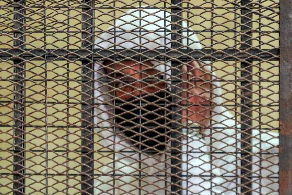 (FILES) In this file photo taken on March 20, 2022 Egyptian media and real estate tycoon Mohamed el-Amin looks from the defendant’s cage during a trial session over charges of “human trafficking” and “sexual assault” in the Egyptian capital’s eastern suburb of New Cairo on March 20, 2022. AFPPIX