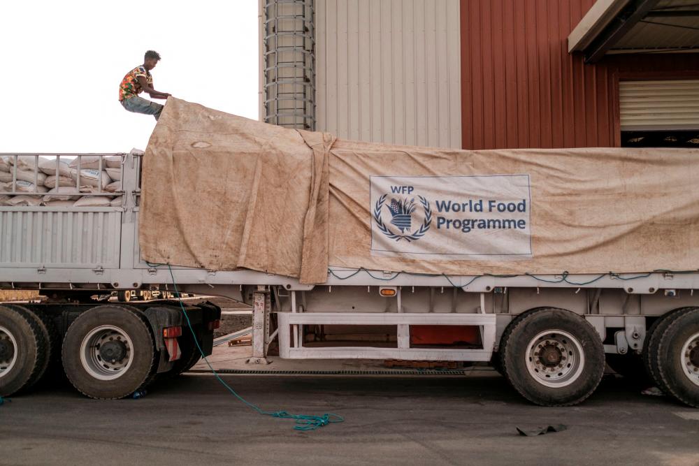 (FILES) In this file photo taken on June 09, 2022 A worker covers a truck full of sacks of grain in a warehouse of the World Food Programme (WFP) in the city of Abala, Ethiopia. AFPPIX