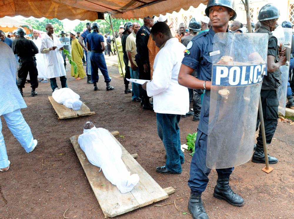 In this file photo taken on October 02, 2009 a policeman stands next to the bodies of people shot dead by Guinea junta forces on September 28, 2009 in front of the Conakry great mosque/AFPPix