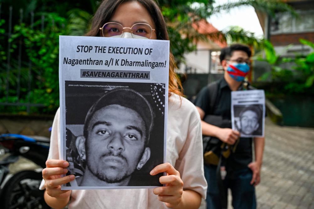 (FILES) In this file photo taken on November 3, 2021, activists hold placards before submitting a memorandum to parliament in protest of the impending execution of Nagaenthran K. Dharmalingam, sentenced to death for trafficking heroin into Singapore, in Kuala Lumpur. AFPPIX