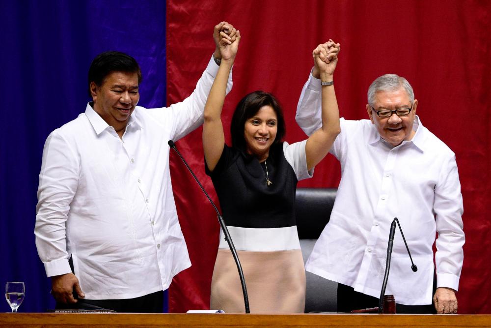 This file photo taken on May 30, 2016 shows Philippine Senate president Frank Drilon (L) and House Speaker Feliciano Belmonte (R) raise the hands of Vice President-elect Leni Robredo (C) during her proclamation as vice president at the Session Hall of the House of Representatives in Manila. - AFPpix