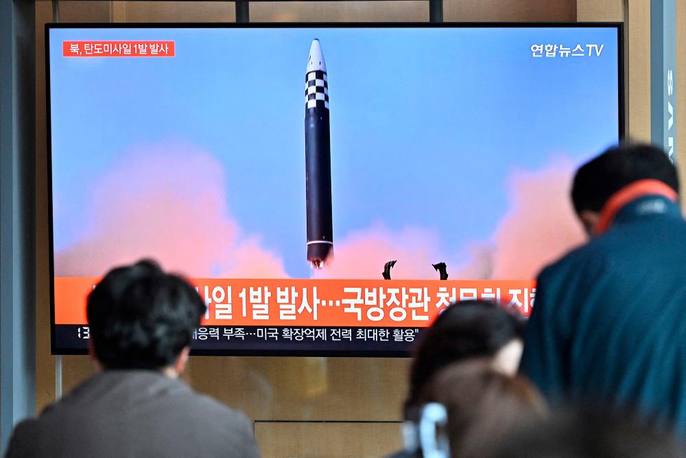 (FILES) This file picture taken on May 4, 2022 shows people watching a television screen showing a news broadcast with file footage of a North Korean missile test, at a railway station in Seoul. AFPPIX