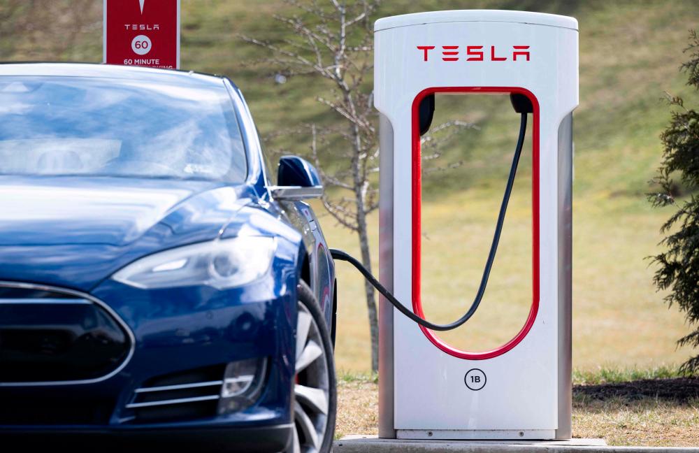 A Tesla Model S sedan is plugged into a Tesla Supercharger electrical vehicle charging station in Falls Church, Virginia, February 13, 2023/AFPPix