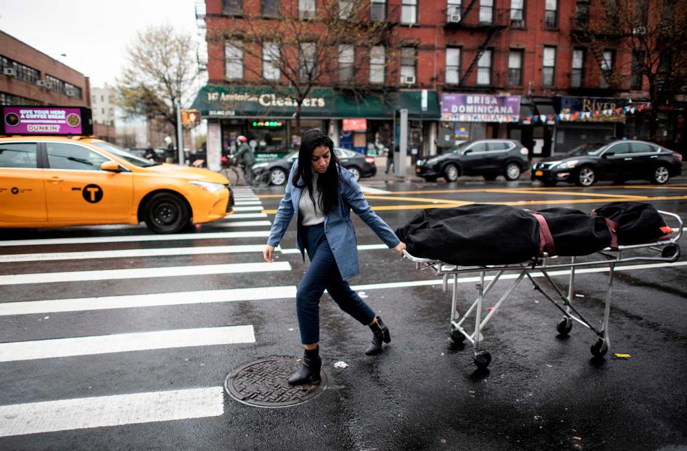 (FILES) In this file photo taken on April 24, 2020, Alisha Narvaez Manager at International Funeral &amp; Cremation Services transports a body to the funeral home in the Harlem neighborhood of New York City. AFPPIX