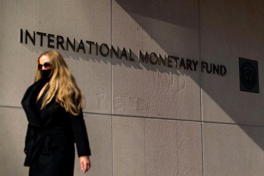 (FILES) In this file photo taken on April 05, 2021 a woman walks past an International Monetary Fund headquarters(IMF) building in Washington, DC. With the recent wave of price increases likely to remain a concern for some time, the US Federal Reserve should raise interest rates sooner, the IMF said December 3, 2021. AFPpix