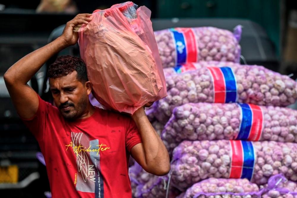Workers transport food grains and other essential goods at a market after authorities relaxed the ongoing curfew for a few hours in Colombo on May 12. - AFPPIX