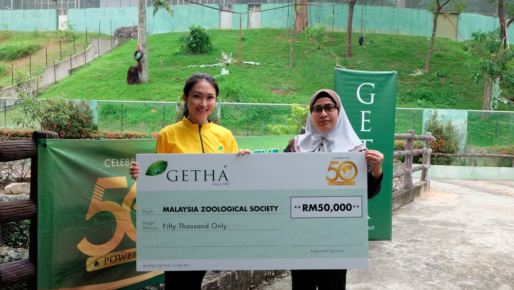 From left: Tan hands over the mock cheque to Linda at Zoo Negara.