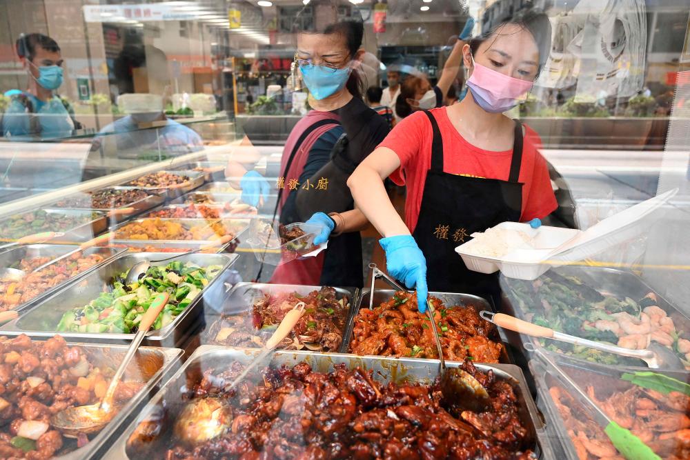 This photo taken on September 18, 2022 shows workers serving customers low-priced two-dish mealboxes at Kitty Chan’s restaurant in Hong Kong. AFPPIX