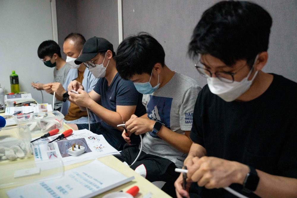 This photo taken on September 3, 2022 shows students learning basic electrical wiring skills while attending a home-repair class in Hong Kong. AFPPIX