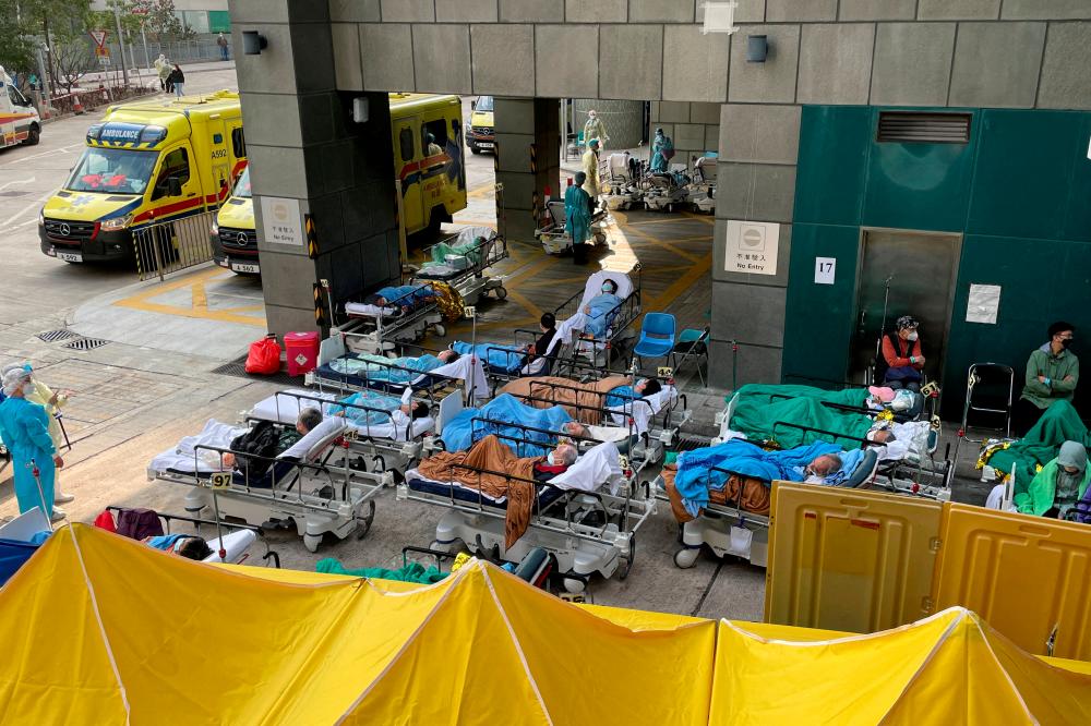 FILE PHOTO: Patients wearing face masks lie in bed at a makeshift treatment area outside a hospital, following the coronavirus disease (Covid-19) outbreak in Hong Kong, China February 16, 2022. REUTERSpix