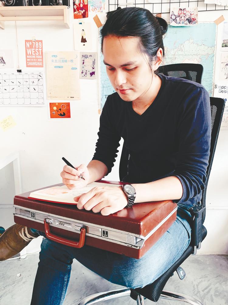 Lai drawing on top of a briefcase. – Courtesy of Lai Theng Sen