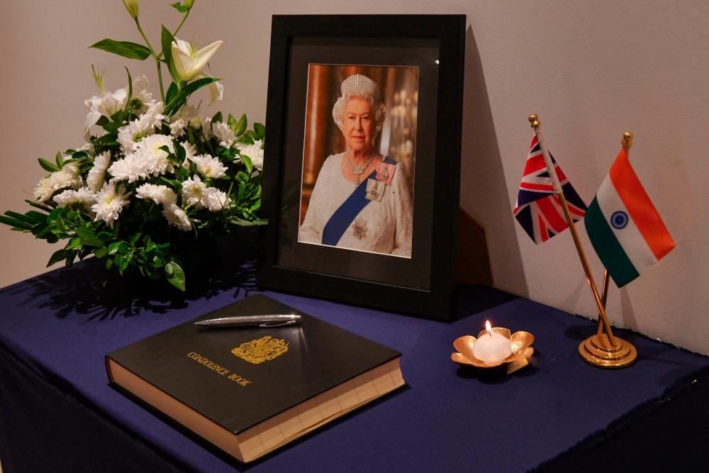 A portrait of Queen Elizabeth II placed next to a condolence book at the British Deputy High Commissioner’s Residence in Bangalore on September 9, 2022. - AFPPIX