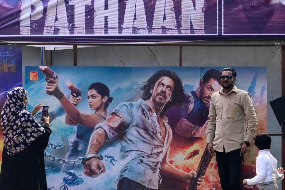 Moviegoers pose for pictures in front of a poster of the Bollywood movie ‘Pathaan’ outside a cinema hall in Prayagraj on January 25, 2023/AFPPix