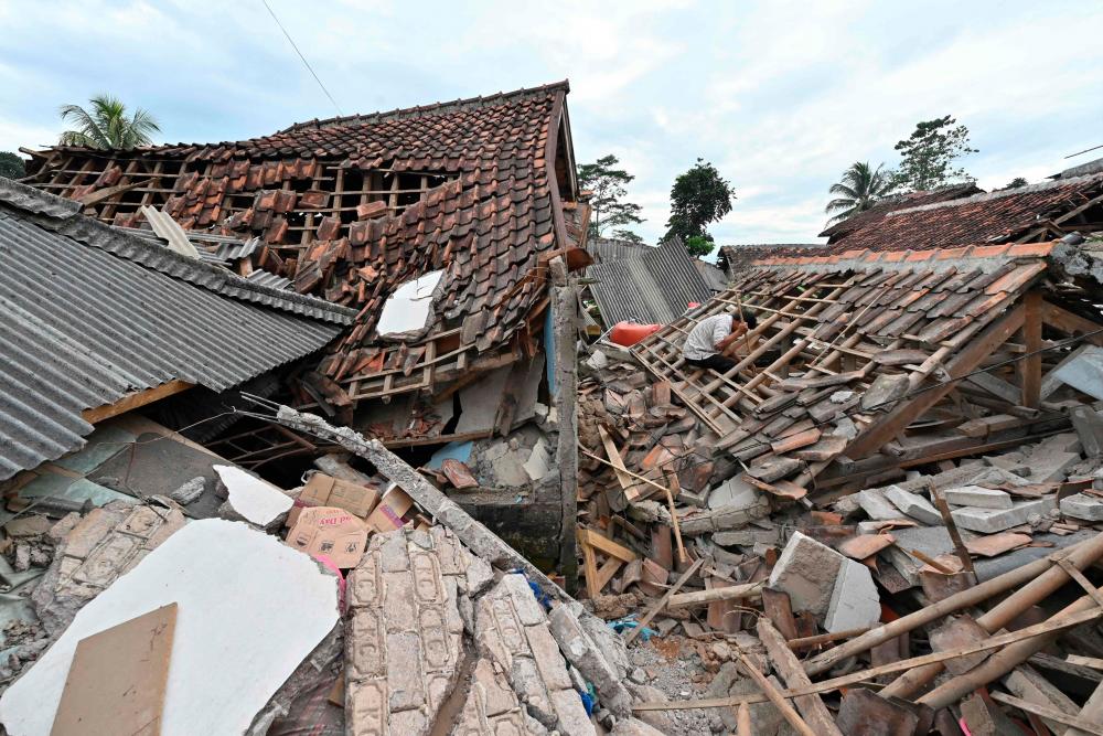 A man (R) sifts through the rubble of a collapsed house in Cugenang, Cianjur on November 23, 2022, following a 5.6-magnitude earthquake on November 21/AFPPix