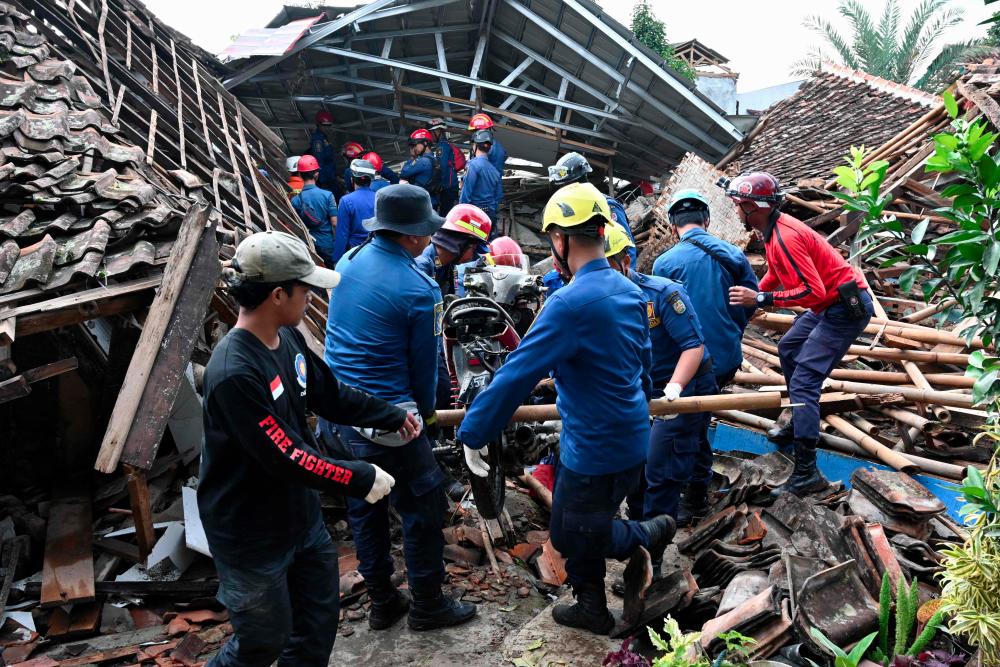 Rescue personnel remove a motorcyle as they work to find a missing child believed to be trapped in the rubble of a collapsed house at Cugenang in Cianjur, West Java on November 24, 2022, following a 5.6-magnitude earthquake on November 21. - AFPPIX