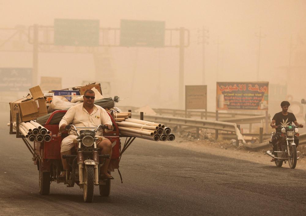 People ride during a sandstorm in the town of Khalis, in Iraq’s Diyala province, on July 3, 2022. AFPPIX