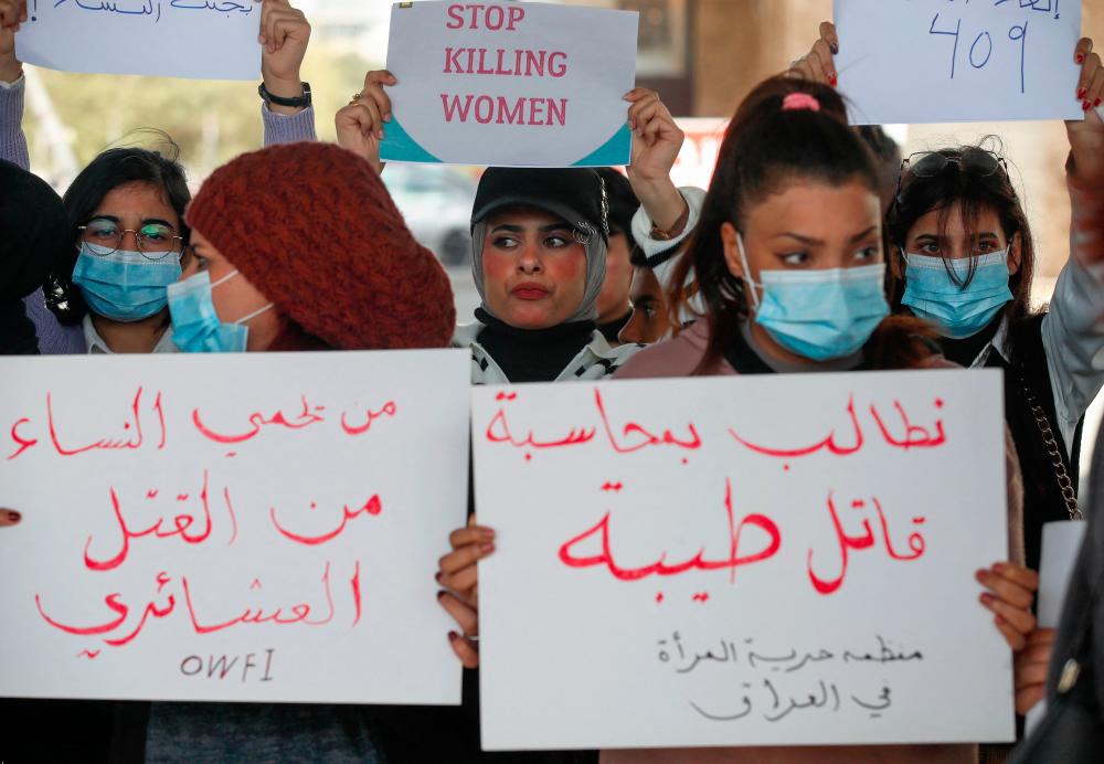 Iraqi women's rights activists lift placards during a rally near the Supreme Judicial Council in Baghdad on February 5, 2023, to protest the killing of Iraqi youtuber Tiba al-Ali by her father in Diwaniyah. - AFPPIX