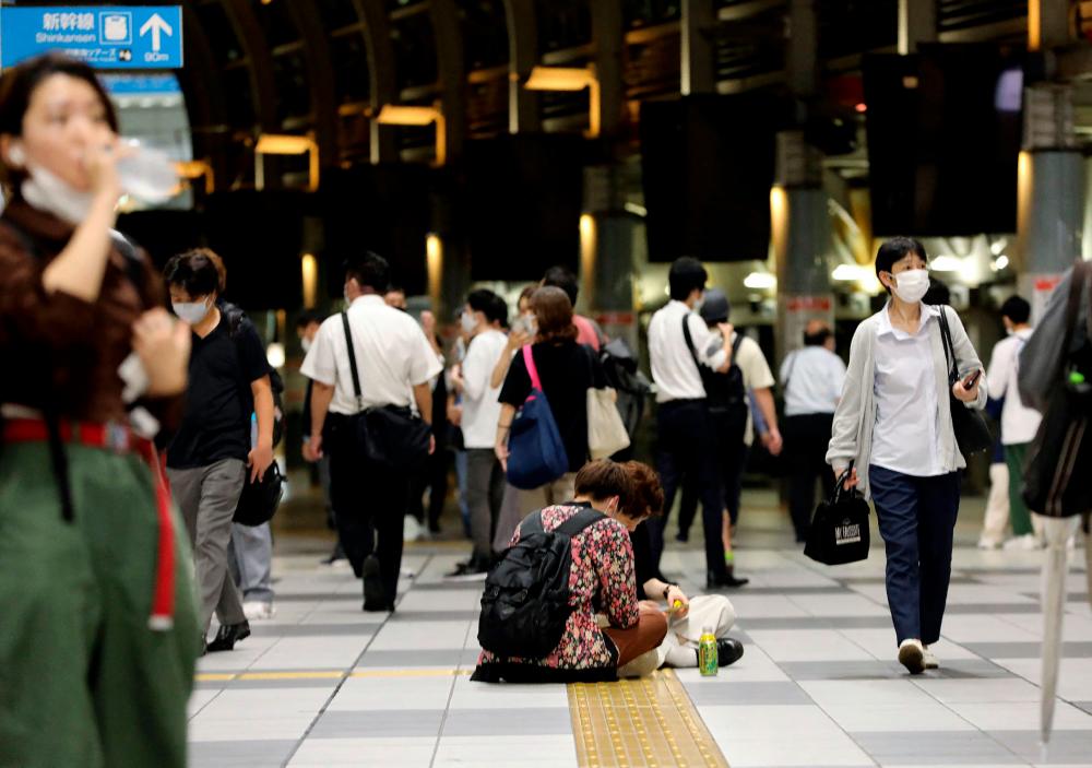 Passeners sit on the floor at Shinagawa train station in Tokyo on early October 8, 2021 as train services are suspended after a 6.1-magnitude earthquake in the Japanese capital and surrounding areas/AFPPix