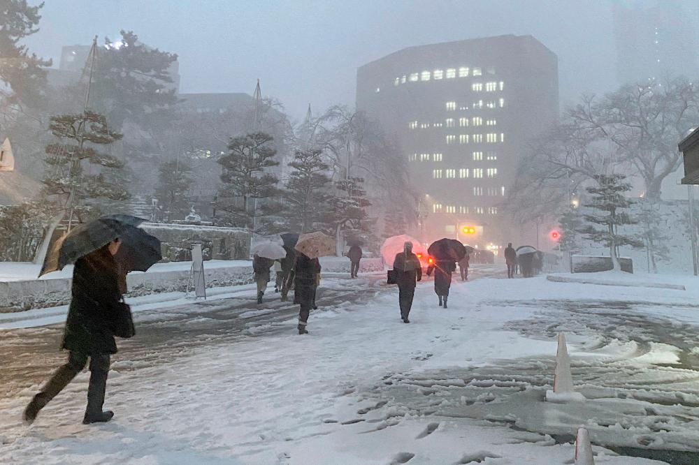 People make their way home in the snow in the city of Fukui, Fukui prefecture on the western coast of Japan on January 24, 2023, as parts of the country brace for a severe winter storm/AFPPIX