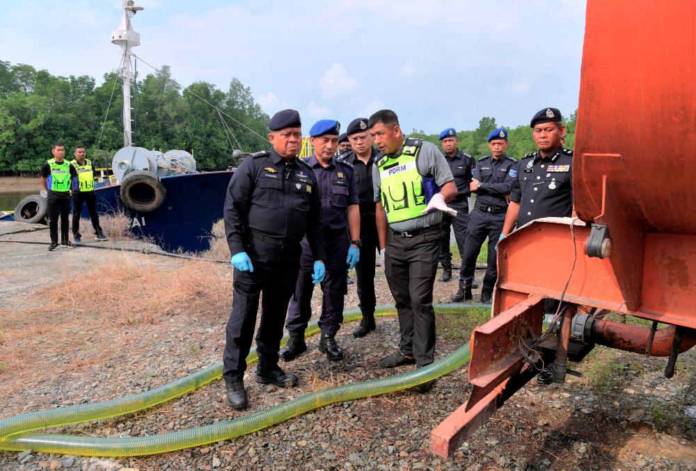 Ketua Polis Johor Datuk Kamarul Zaman Mamat (tiga, kiri) melihat tempat transit penyeludupan minyak diesel bersubsidi di sebuah premis di Sungai Bauk, Tanjung Berlungkor hari ini. fotoBERNAMA