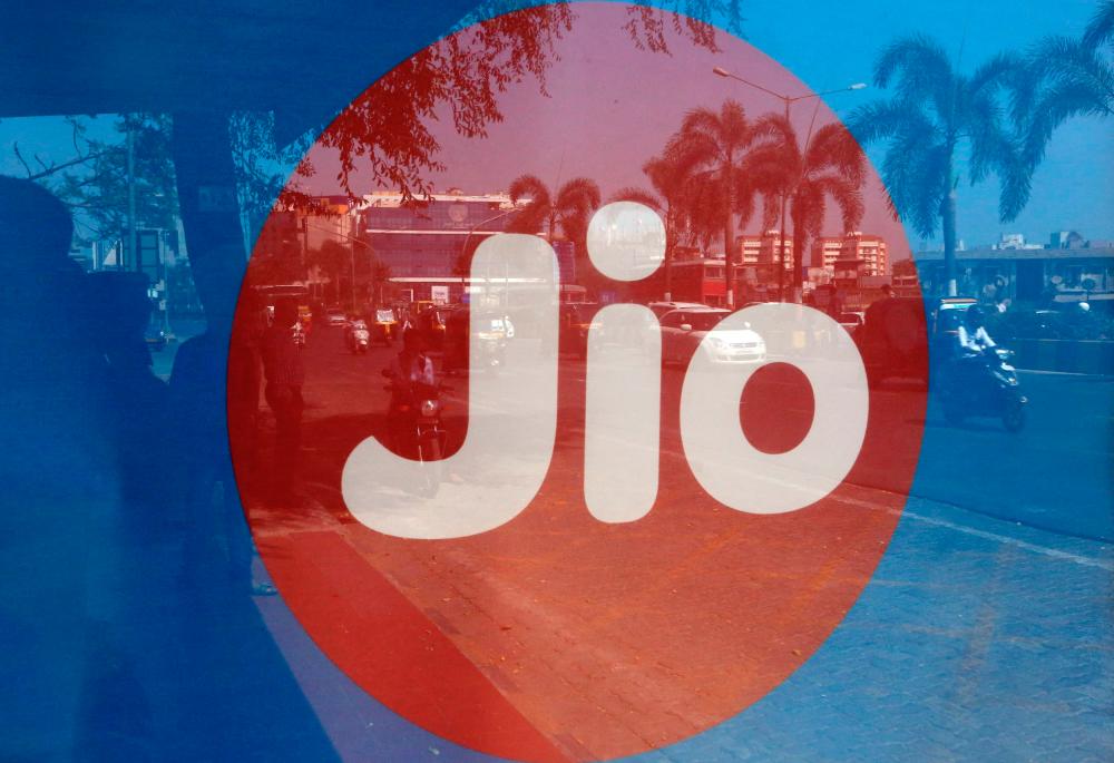 Commuters are reflected on an advertisement of Reliance Industries’ Jio telecoms unit, at a bus stop in Mumbai. – Reuterspix